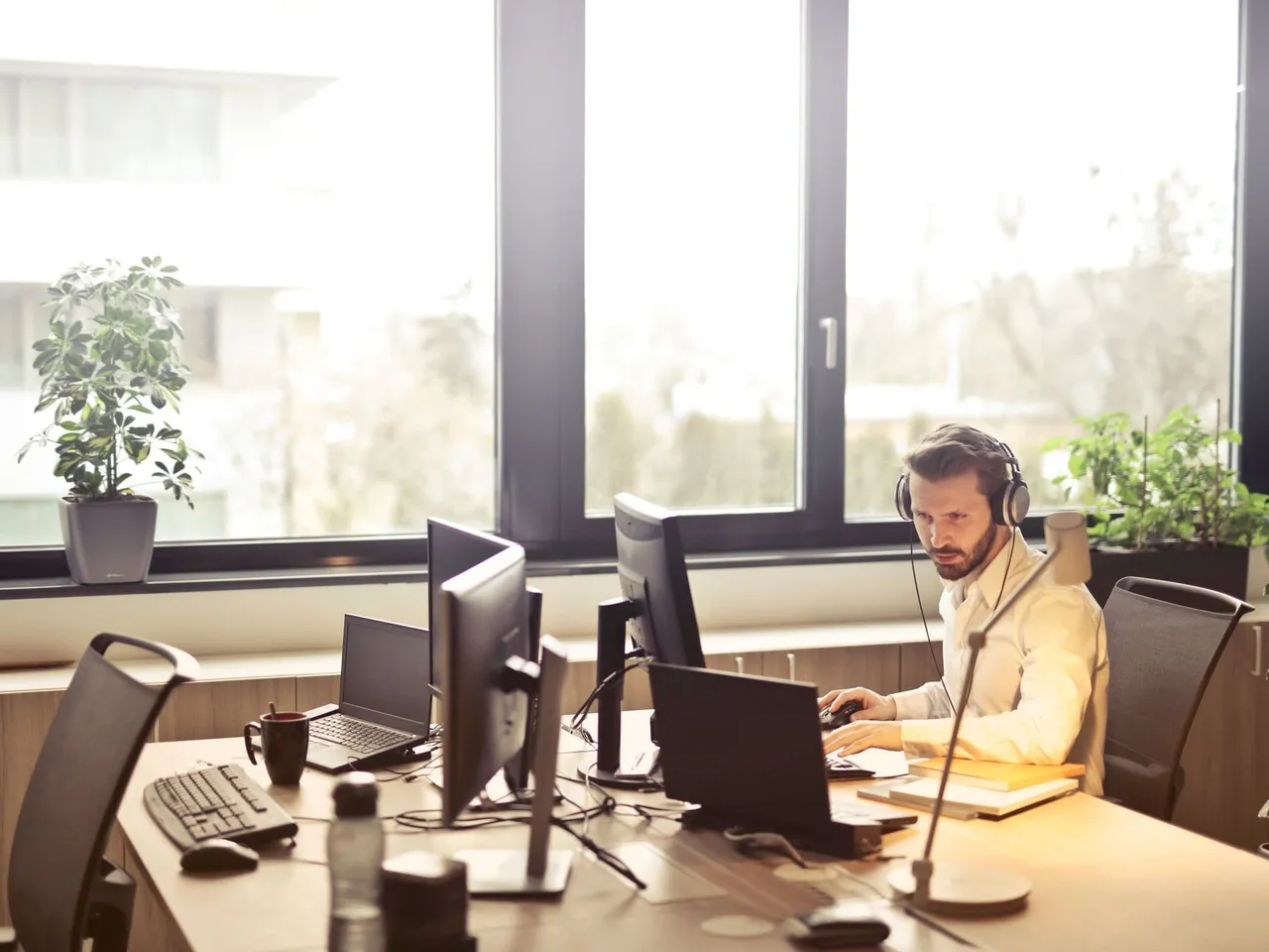 IT-Techniker mit Headset an mehreren Bildschirmen in einem hellen Büro