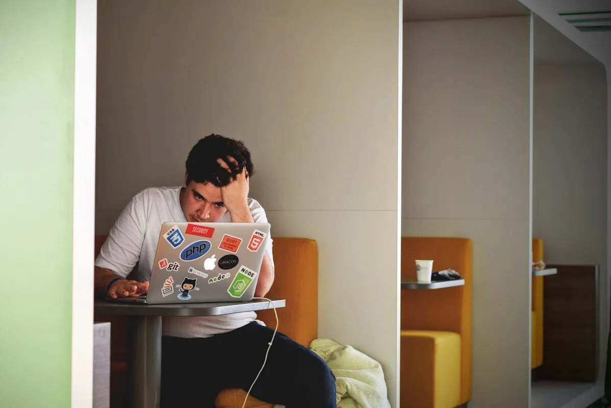 Überforderter IT-Support-Mitarbeiter am Schreibtisch